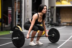 A person in athletic wear performs a squat with a barbell in a gym, showcasing strength and focus.