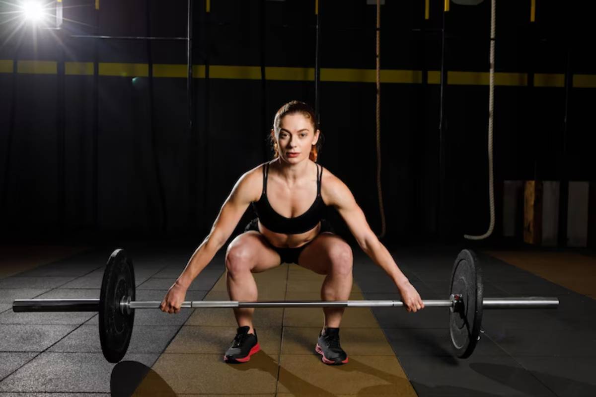 A person in athletic wear is performing a squat lift with a barbell on a gym floor, showcasing strength and focus in a training environment.